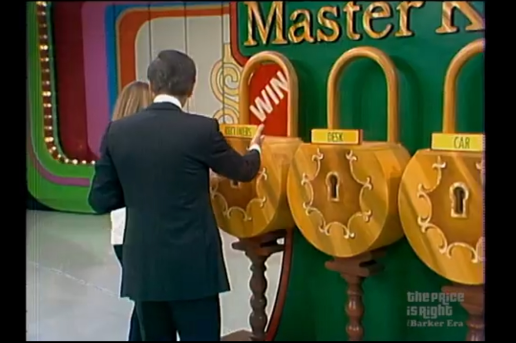 Contestant and host interact with the Master Key game, showcasing three locks labeled for prizes: recliners, desk, and car, with a 'WIN' indicator visible.