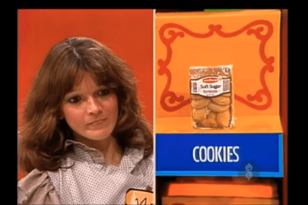 Contestant Mary looks intently at a display of cookies labeled 'Soft Sugar' while considering her options for the game 'Pick a Pair'.