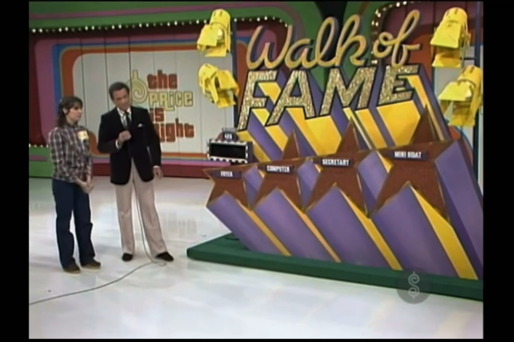 Contestants stand at the 'Walk of Fame' game on 'The Price is Right' with prizes displayed.