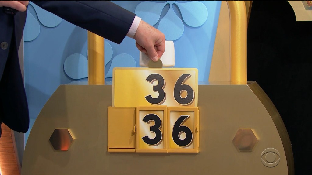 A hand is placing a card with the number '36' onto a display that shows a combination of numbers, with another '36' visible below it, against a colorful backdrop.