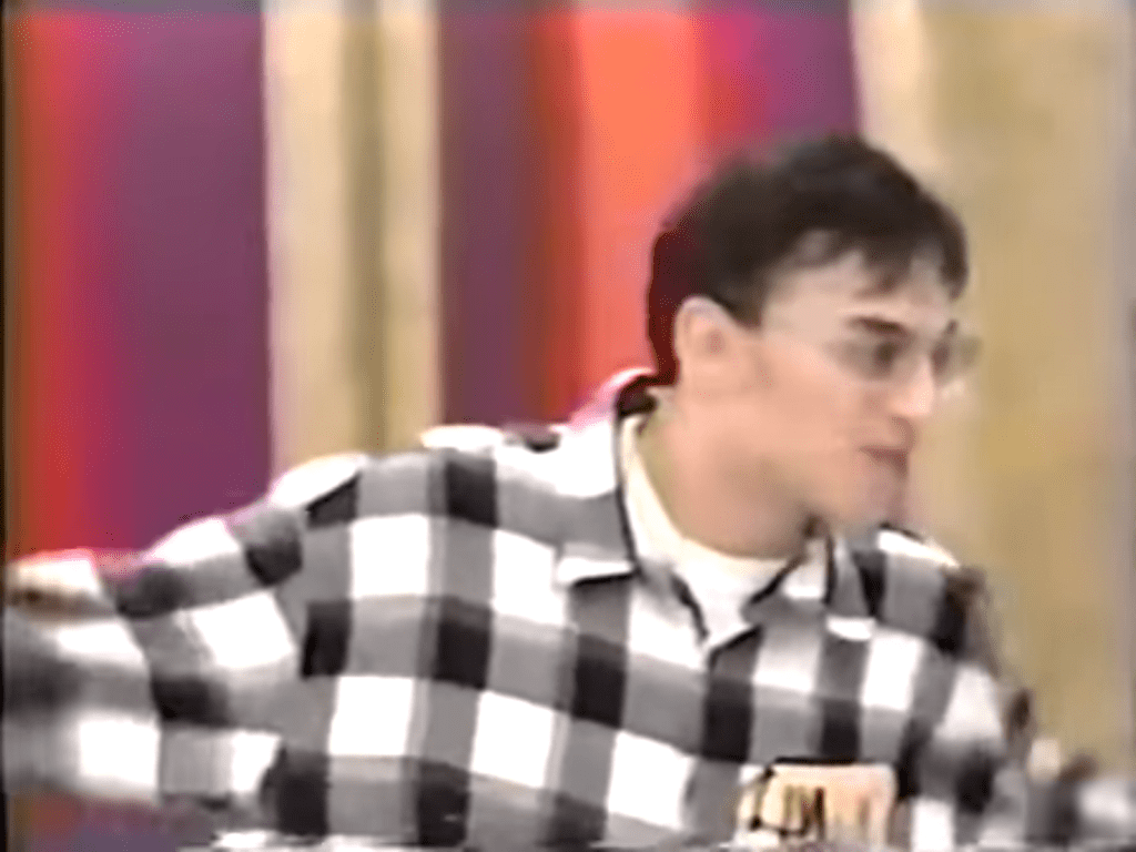A contestant enthusiastically gestures while playing Pick-a-Pair on The Price is Right, wearing a black and white checkered shirt.