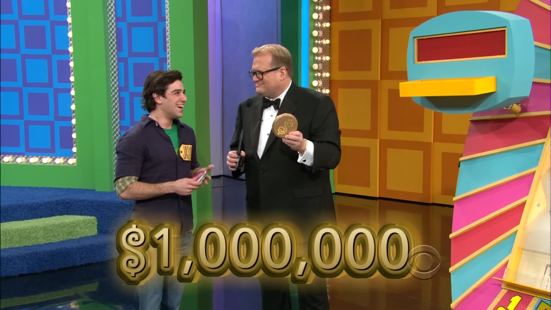 Contestant smiling and holding a Plinko chip while standing next to the host on the set of The Price is Right, with a large cash prize of ,000,000 displayed in gold text below.