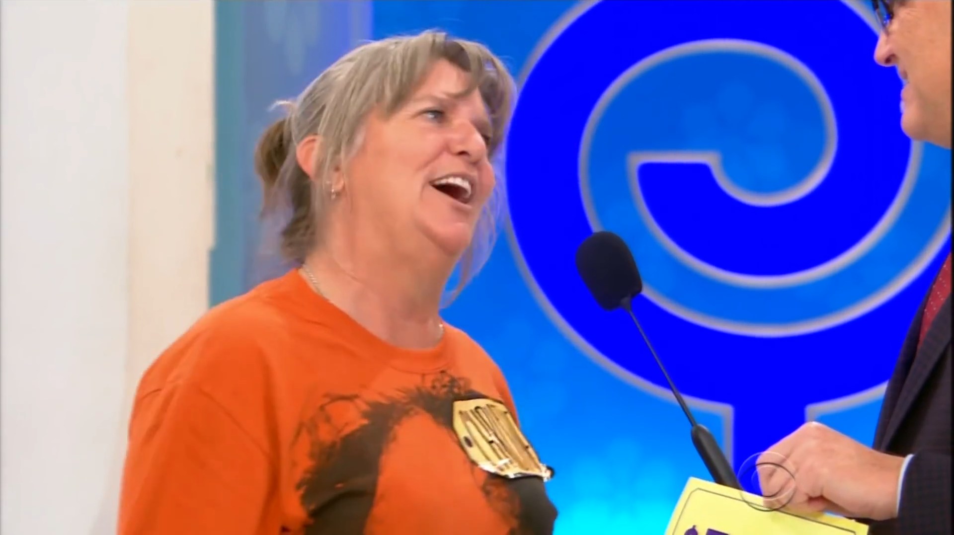 A contestant smiles and interacts with the host during a game show setting.