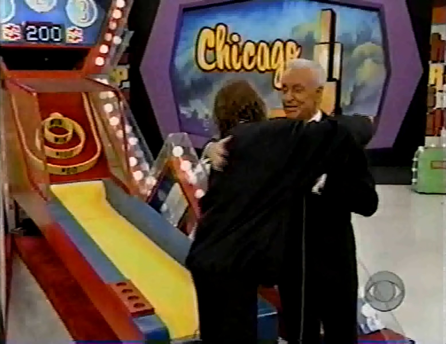 A contestant and host embrace in front of the Super Ball game ramp on The Price is Right, featuring colorful graphics and a scoreboard.