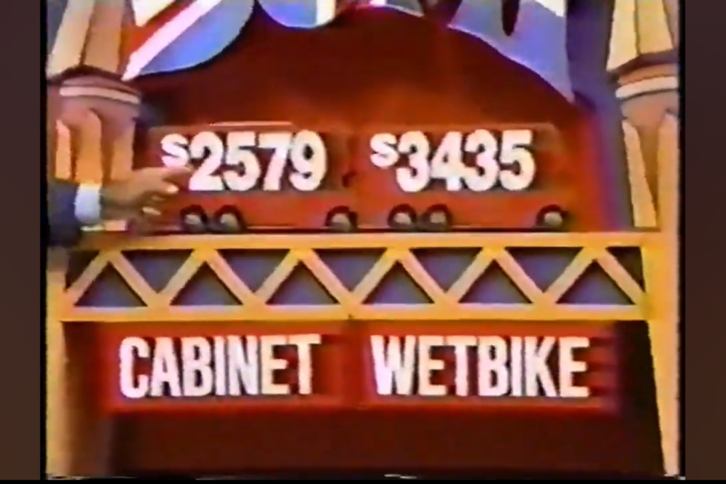 Price display board showing 79 for 'CABINET' and 35 for 'WETBIKE' with a hand pointing to the prices.