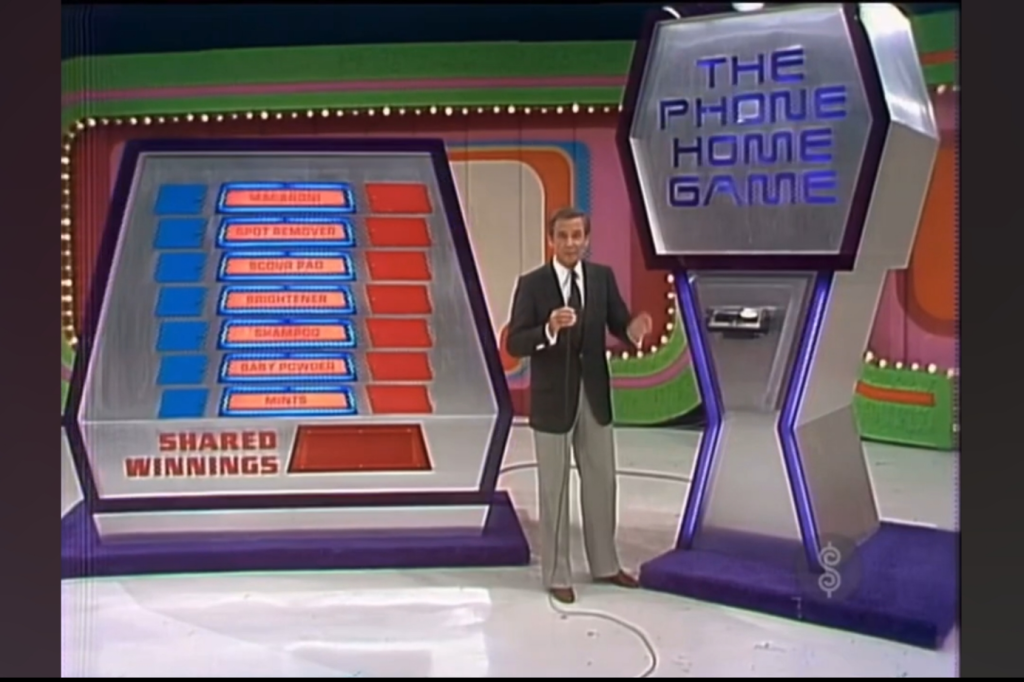 The Phone Home Game display on the set of The Price is Right with grocery items and shared winnings, featuring Bob Barker explaining the rules.