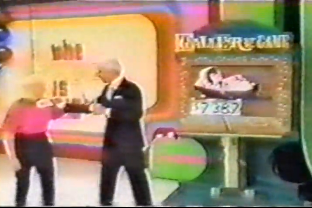 A game show host and a contestant interact on stage, with a colorful background and a game display showing a prize amount of 7,837.
