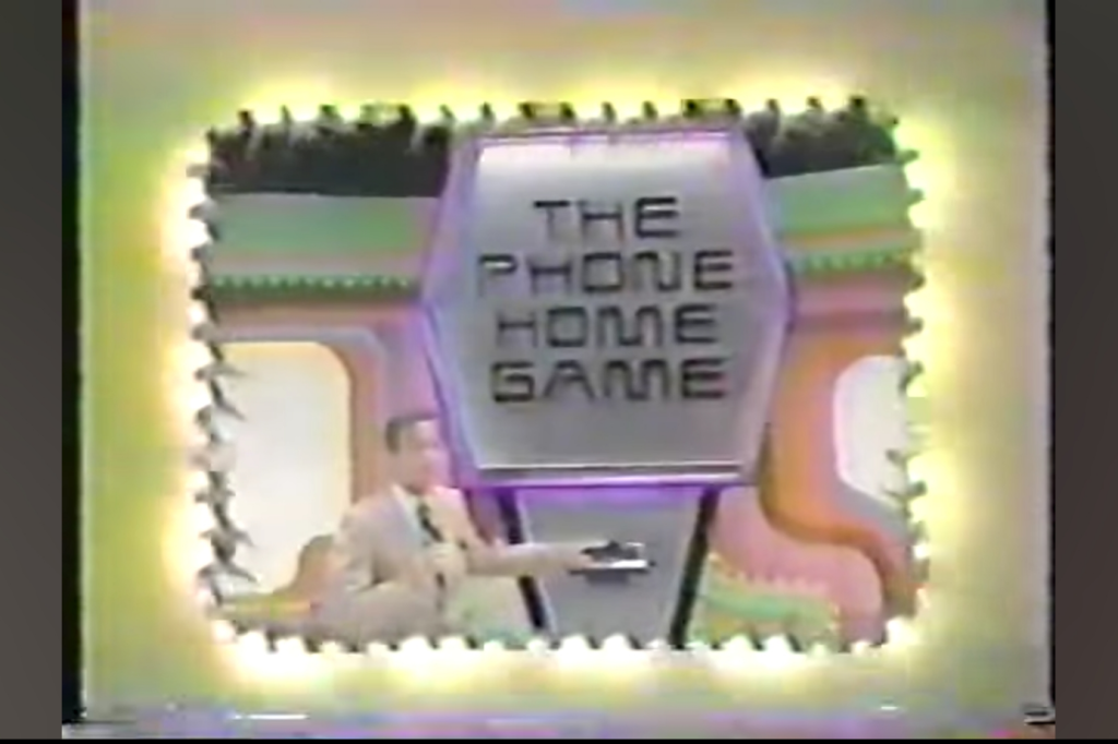 Bob Barker presents 'The Phone Home Game' sign in a colorful set with decorative lighting.