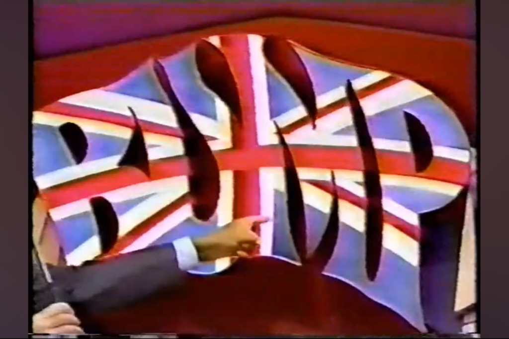 A large three-dimensional sign that reads 'BUMP' with a design featuring the Union Jack flag, set against a colorful background, while Bob Barker gestures towards it.