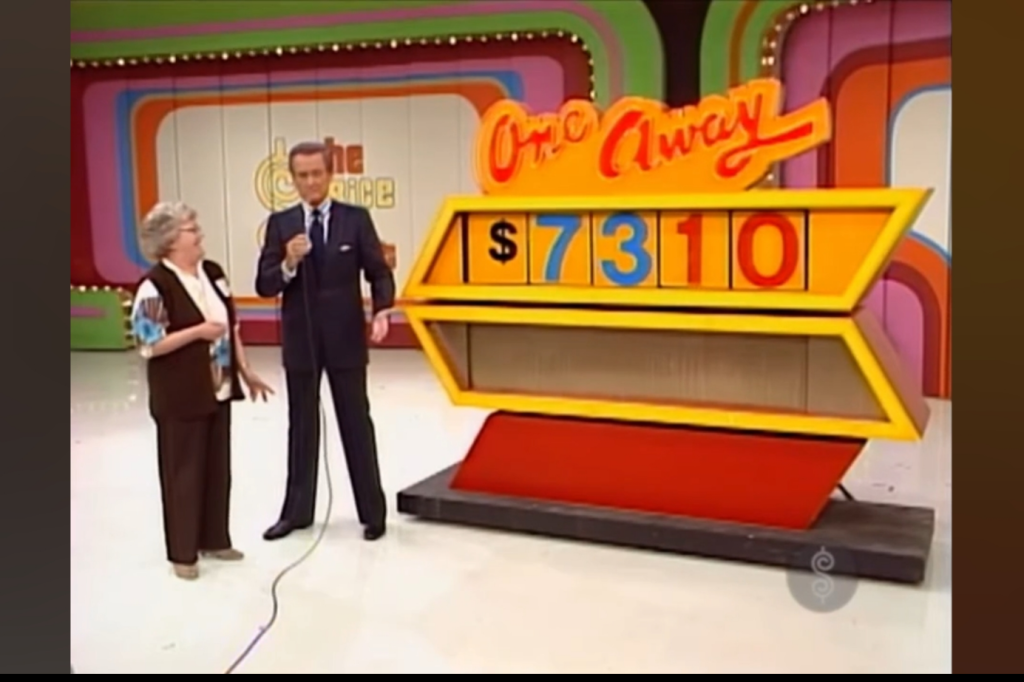A contestant stands next to the host on stage in front of a large game board displaying the title 'One Away' and the price 10, with colorful numbers and a vibrant background.