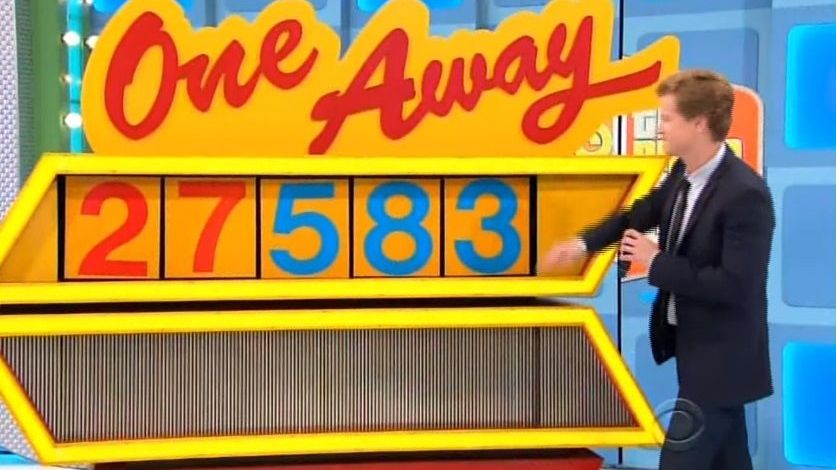 A contestant playing the game 'One Away' on a television show, with the numbers 27583 displayed on a colorful, oversized game board.