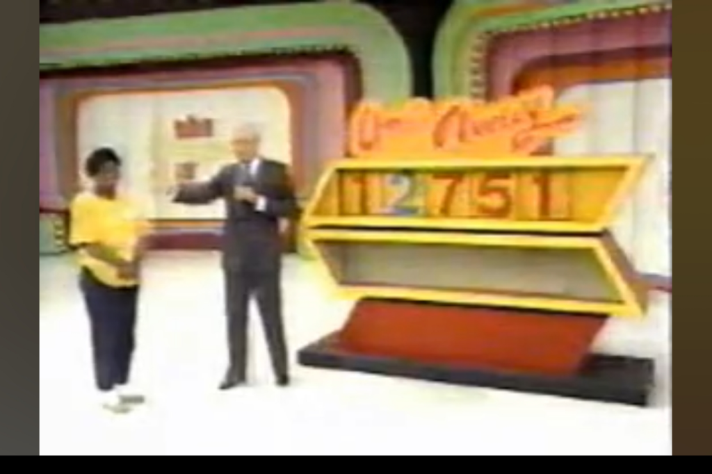 Contestant stands beside host Bob Barker during the One Away game, featuring a display showing the incorrect car price of ,751.