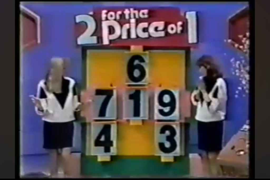 Two models present numbers on a game show board titled '2 For the Price of 1', having set the price to be 9.