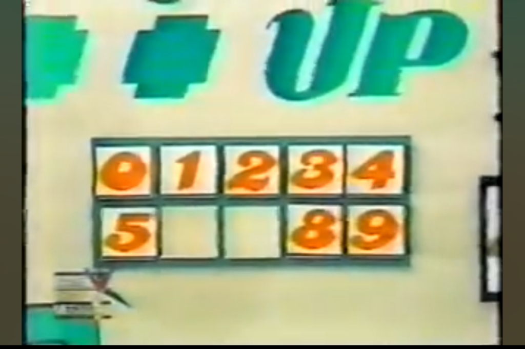 Display board for the 'Add 'Em Up' game, featuring numbered tiles 0-9 and the game's title.