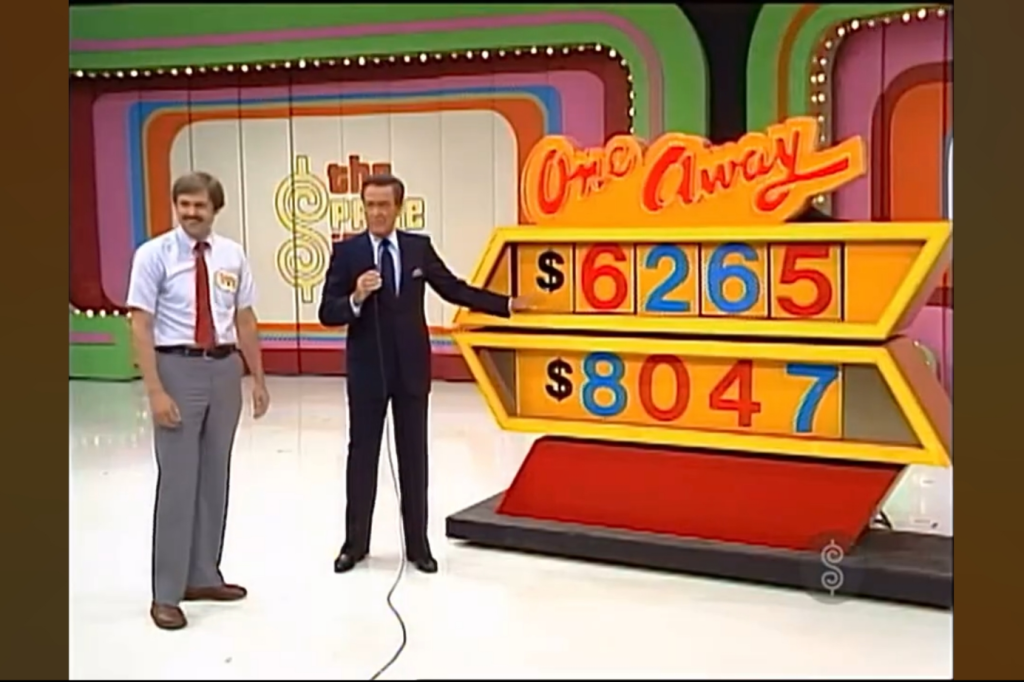A scene from 'The Price is Right' featuring two contestants standing beside the 'One Away' game board, displaying incorrect car prices of ,265 and ,047. The host gestures towards the game board.
