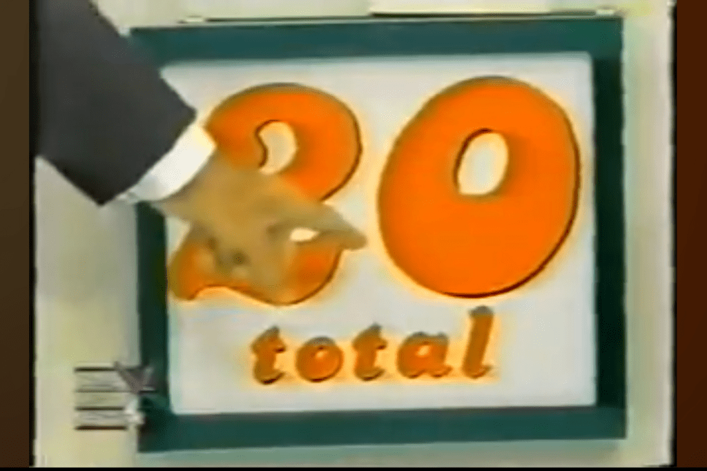A hand pointing at a display board showing the number 20, indicating the total needed for the game 'Add 'Em Up'.