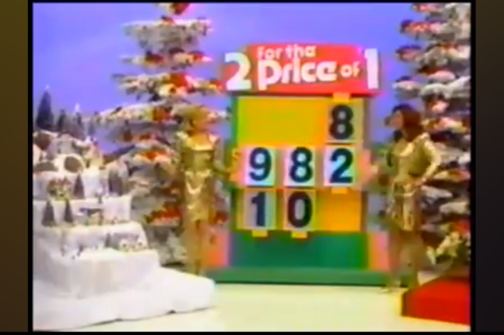 A vibrant game show set featuring two models in gold outfits next to a colorful price board, with snowy trees and holiday decorations in the background.