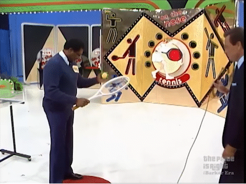 A man bouncing a tennis ball and hitting it towards a target, with it missing and bouncing wildly off the game's set and flying toward the audience.