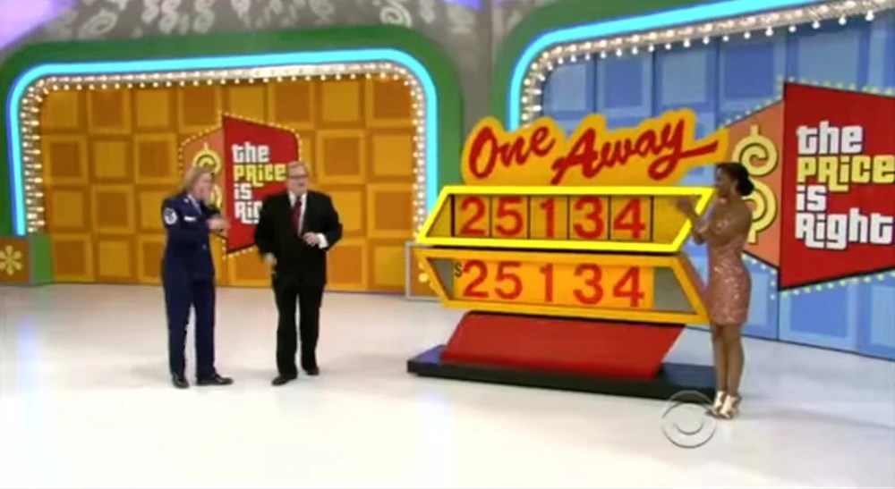 Contestant plays 'One Away' on The Price is Right, with host presenting the game board showing a car price of 25134 with digits displayed above.