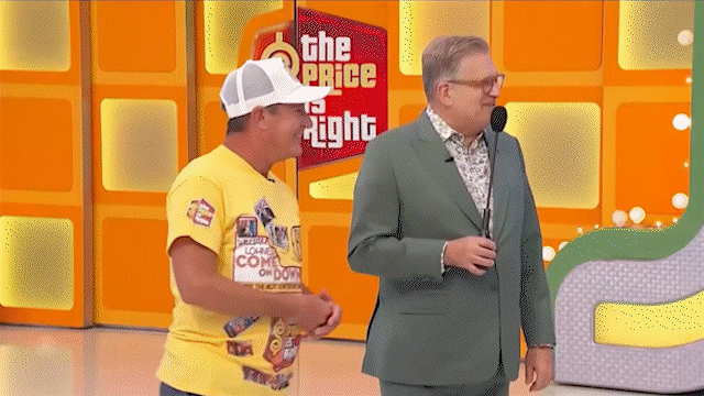 Drew Carey joking that model Alexis Gaube needs to move the blocks up instead of down, as Alexis shoots him a playful glare before rotating the number.