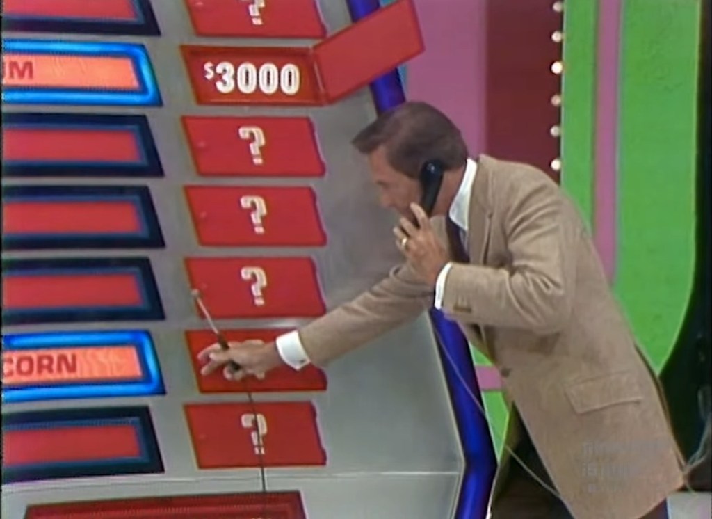 Contestant interacting with a phone during The Phone Home Game on The Price is Right, selecting a product from a game board.