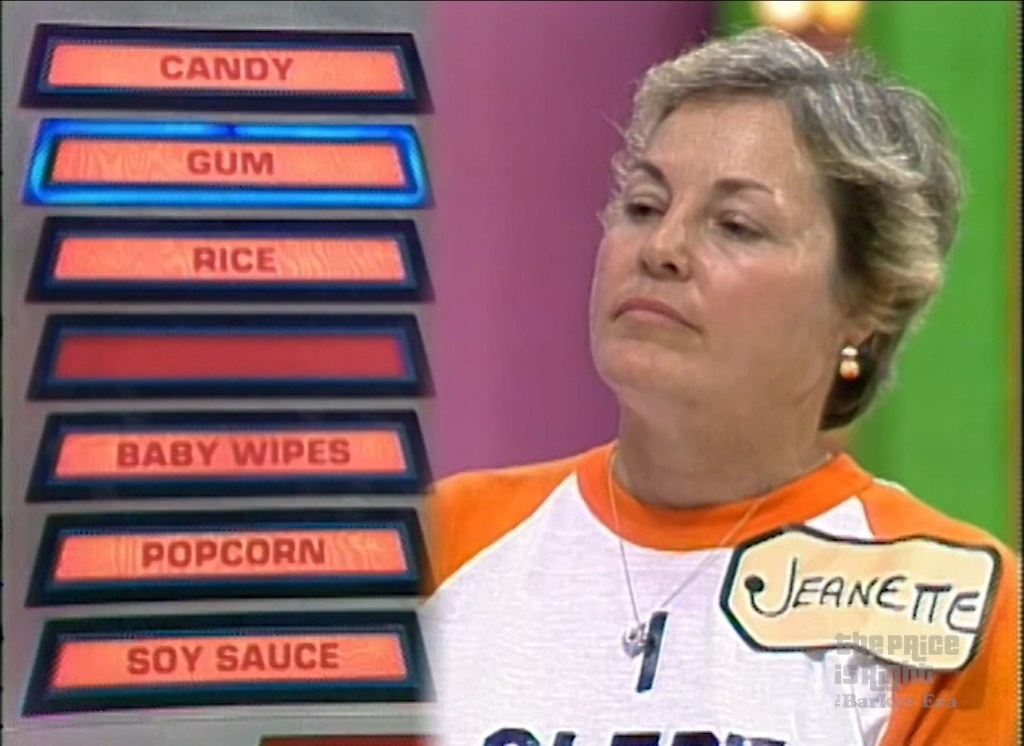 A contestant named Jeanette focusing on a pricing game board displaying seven grocery items: candy, gum, rice, baby wipes, popcorn, and soy sauce, during a segment of The Price is Right.