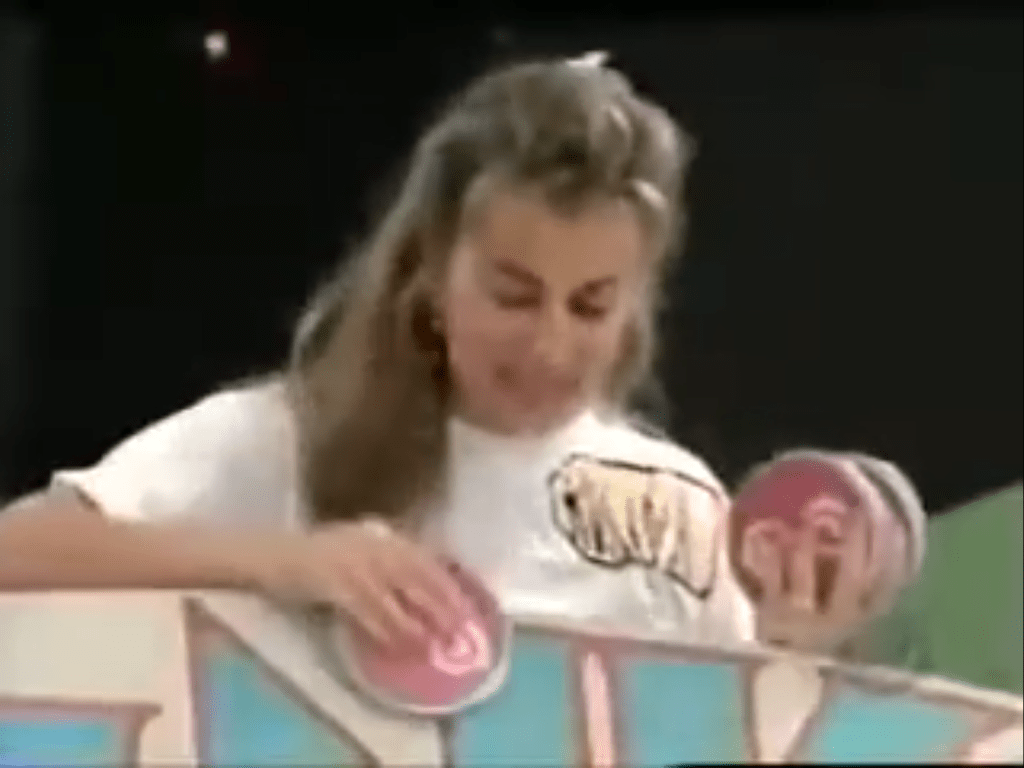 'Rosina the Plinko Lady' holding multiple Plinko chips while preparing to play the game on stage.