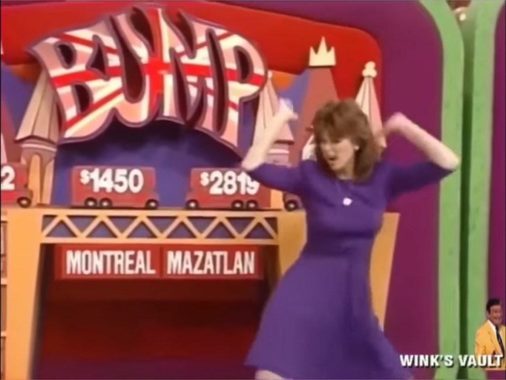 Holly Hallstrom in a purple dress dancing on stage in front of a colorful game show backdrop with the word 'BUMP' and displayed monetary values.