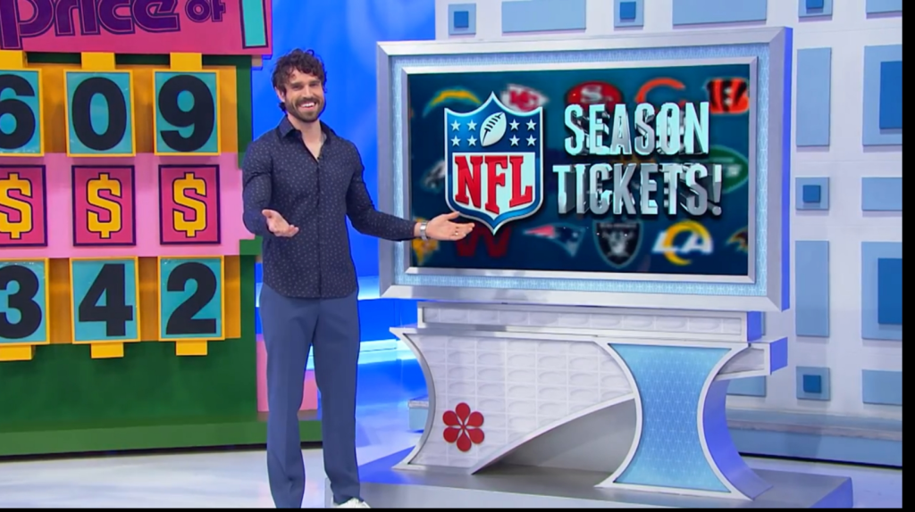 A host smiling and gesturing in front of a screen displaying 'NFL Season Tickets!' with various team logos in the background, alongside a game board with dollar amounts.