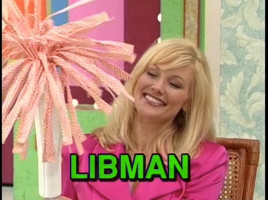 A woman smiling while holding a colorful cleaning tool with a large, fluffy head, displaying the word 'LIBMAN' in bold green letters.