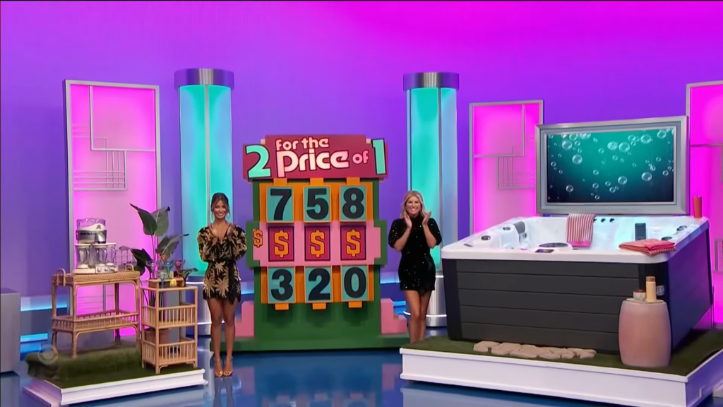 A colorful game show set featuring a large price display reading '2 for the Price of 1' with numbers 758 and 320, and two enthusiastic models standing beside a hot tub and a bar cart with plants.